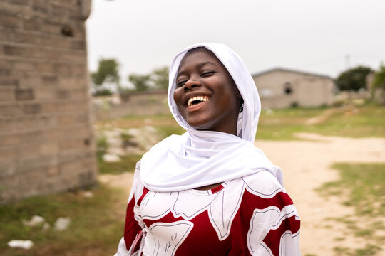 African girl wearing hijab laughing joyfully outdoors