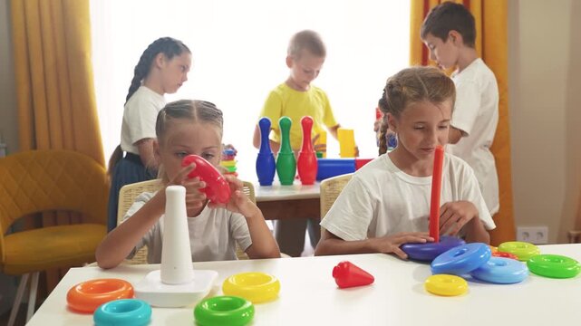 small children play with toys at home. happy family childhood dream concept. a group of little kids develops playing with colorful cubes and pyramids. educational games lifestyle with colored toys