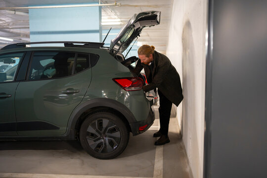 Person loading items into car in parking garage
