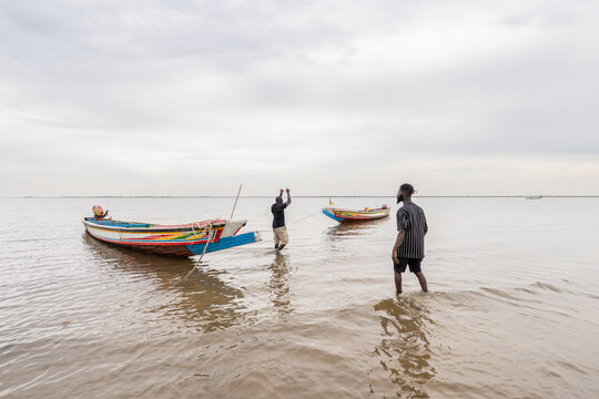 African fishermen pulling traditional pirogue boat in Senegal