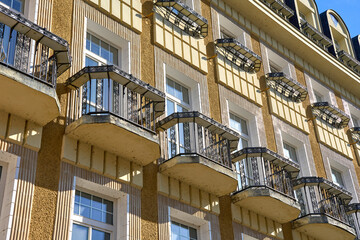 Residential building facade with decorative balconies and geometric details in Karlovy Vary. Exterior view of traditional European architecture under clear blue sky.
