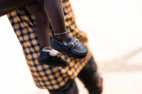 Baby's foot wearing tiny black loafer shoe and ankle bracelet