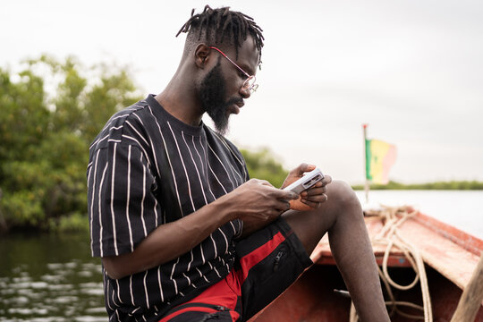 Young African man using smartphone on boat