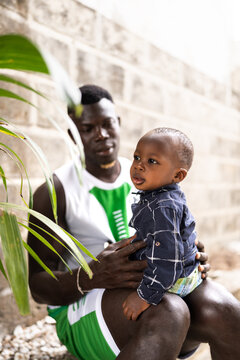 African father holding toddler son in outdoors portrait