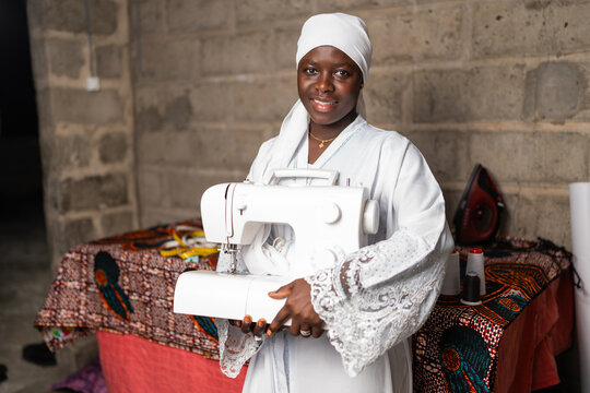 Senegal tailor holding sewing machine empowering African women
