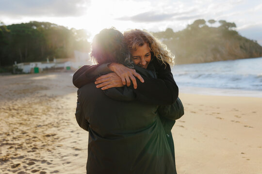 Happy couple hugging on beach during sunset