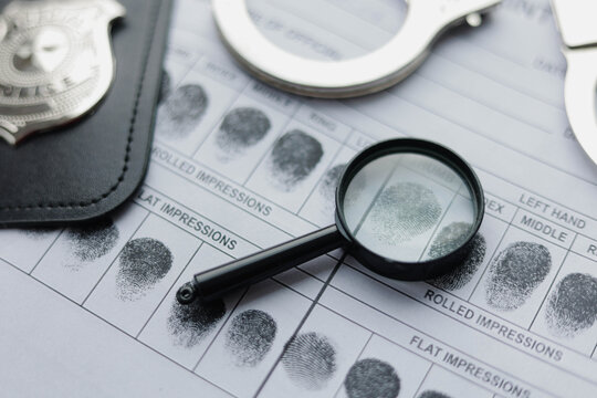 Checking fingerprint card with a magnifying glass. Crime investigation, biometric identification and law enforcement tools.