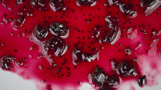 Closeup currant jam glossy red glistening whole berries and seeds syrupy spread on white surface macro food photography vibrant contrast mouthwatering texture and shine