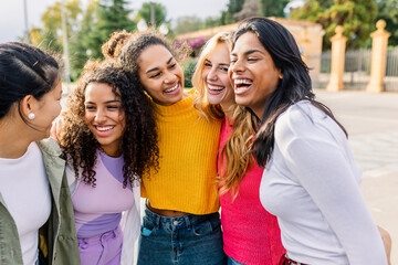 Diverse women hugging and laughing together in the city. Happy female friends enjoying closeness...