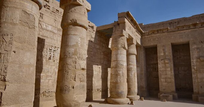 Medinet Habu temple painted ceiling with vulture goddess Nekhbet and hieroglyphs in red orange colors in Luxor Egypt, ancient Egyptian astronomical decorations and cartouches .