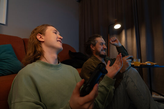 Father and son cheering while playing video games at home