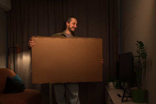 Man holding large cardboard box in cozy living room