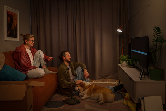 Couple relaxing with dog while setting up new TV at home