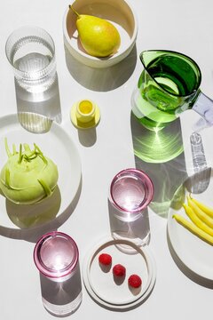 Fresh fruits and vegetables with glassware on white table