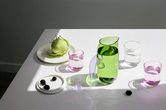 Glass pitcher and glasses on white table with fruit