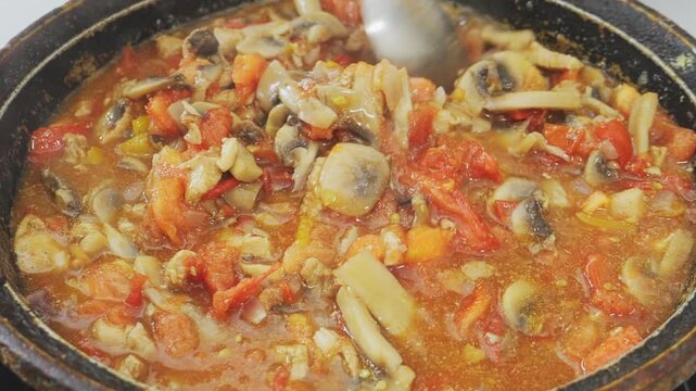 In a deep cast-iron skillet, vegetables and chicken are simmering in sauce