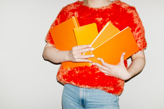Person wearing fashion style furry top and holding books in office