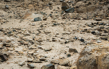 Fototapeta premium Rocky desert ground texture with scattered stones in arid landscape.