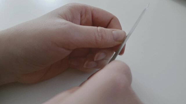 Woman filing fingernail on white table