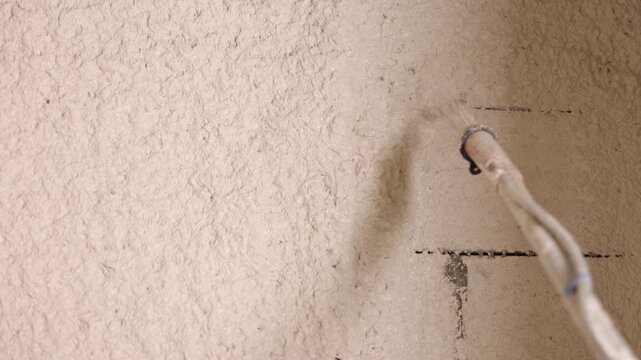Spray plaster, Texture application, Block wall. Close shot spray hose applying fresh textured plaster to indoor concrete block wall.
