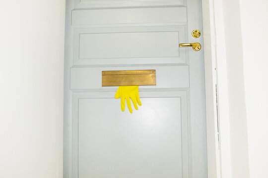 Conceptual photo of yellow plastic gloves peeking from mail box 