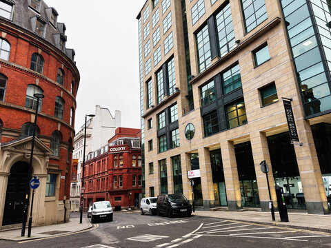 Manchester UK street scene with red brick building and modern glass office tower