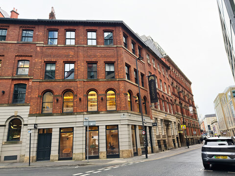 Historic red brick Boss Design Limited building on Manchester Brown street with shops and arched windows in the UK