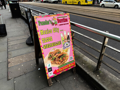 Bright street side sign promoting burritos and tacos in Manchester UK market