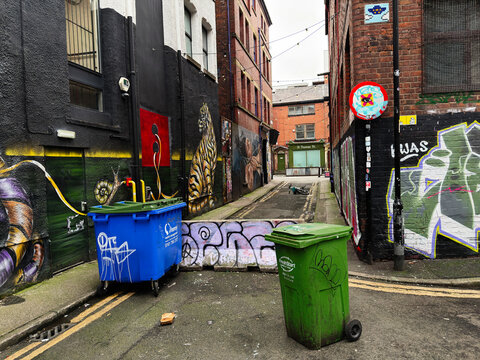 Urban Back Thomas St alley in Manchester featuring graffiti walls, colorful waste bins and street art