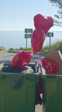 Heart-shaped balloons thrown in trash bin