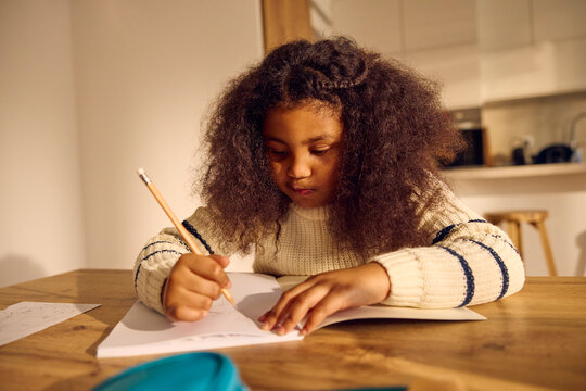 Little girl doing homework in the kitchen