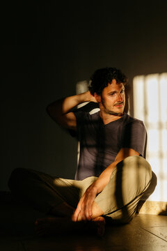 Man sitting on floor with dramatic shadows
