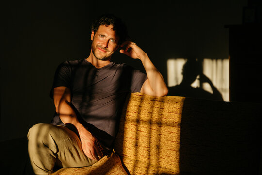 Man on sofa with window light and shadow