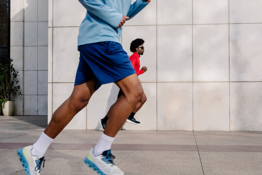 Legs of a fit man in the foreground, with a second runner in the back