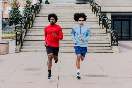 Athletic men running side by side through central Madrid
