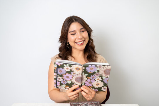 Mujer reflexiva leyendo libreta floral sobre fondo claro