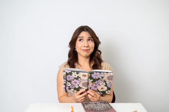 Mujer preocupada leyendo libreta floral sobre fondo claro