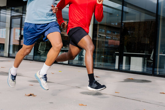 Unknown fit men running together through the streets of central Madrid