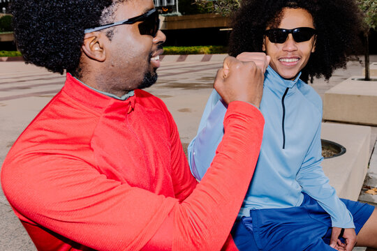 Young athletes sitting on a bench cheerfully exchanging a fist bump