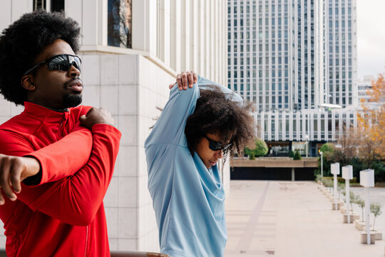 Athletic male friends stretch to warm up before starting a workout