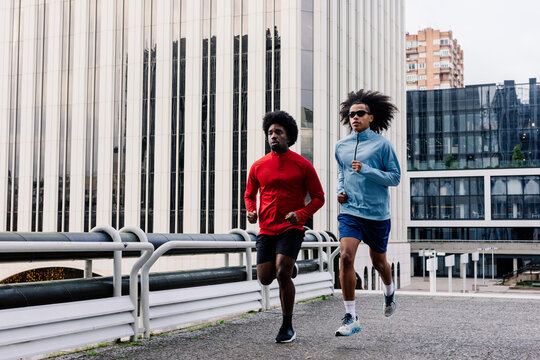Fit men running together through Madrid streets