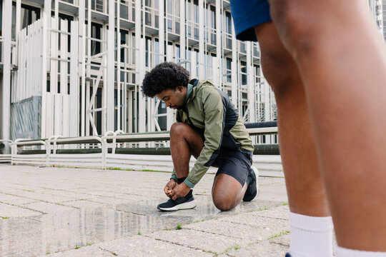 Athlete crouches down to tie his shoelaces before a sports training