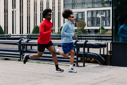 Athletic men running side by side in the commercial area of Madrid