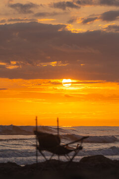 Beach Chair At Sunset With Golden Ocean Waves