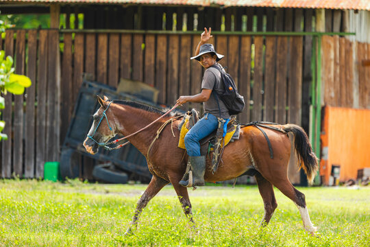 Cowboy Riding Horse Waving At Camera