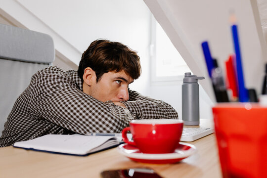 Self-employed worker leaning on his desk with an expression of boredom
