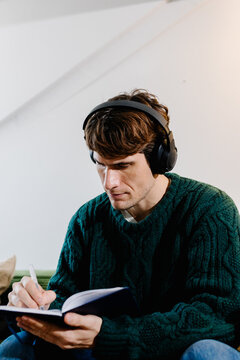 Freelancer writing down daily plans on paper while listening to music