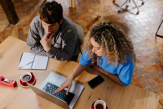 Top-down view of independent workers reviewing content on a computer