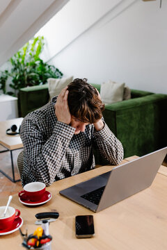 A self-employed person staring at a laptop with a tired expression