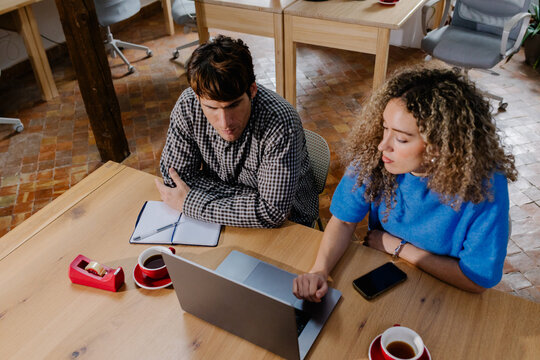 Top-down medium shot of independent workers seated at the same desk